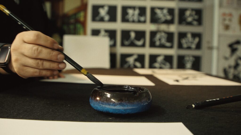Close-up of Madara preparing brush and inkstone for Hisseki-jutsu calligraphy.
