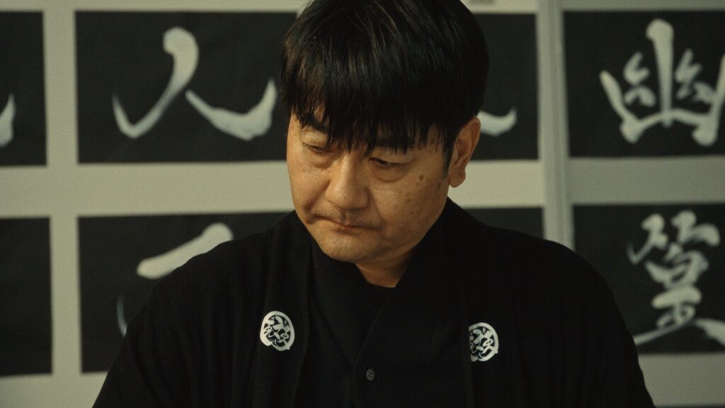 Focused expression of artist Madara during the creation of Hisseki-jutsu calligraphy