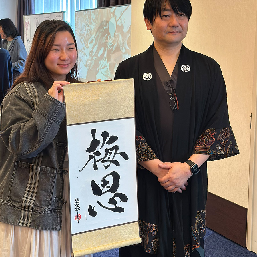 掛け軸の書道作品を持つ海外のお客様の写真