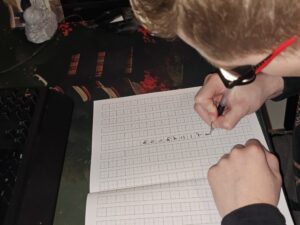 Danny carefully practicing Japanese characters in a notebook while preparing for a custom tattoo calligraphy design