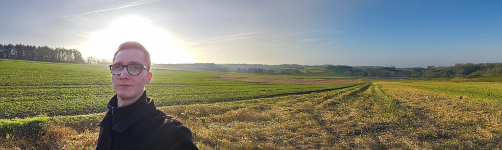 Danny standing within a vast natural landscape, quietly preparing for the beginning of his custom tattoo calligraphy journey