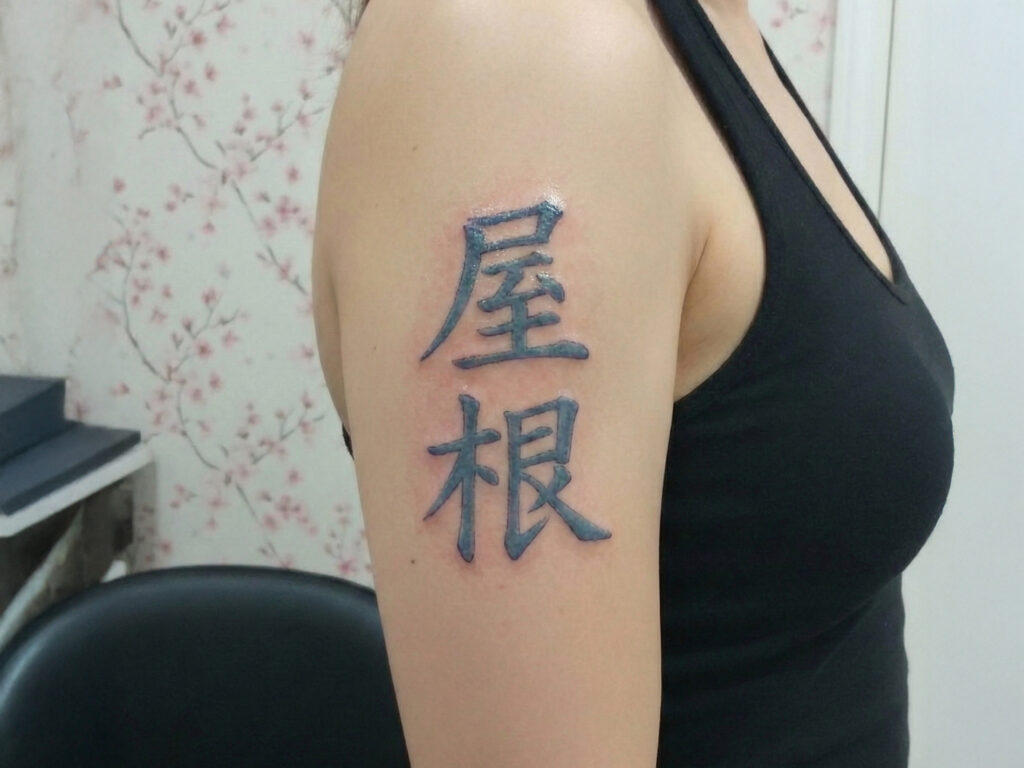 A vertically arranged two-kanji tattoo on the upper arm, with unclear or culturally inconsistent meaning