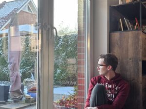 A man sitting by a window, quietly looking outside while reflecting on his inner thoughts